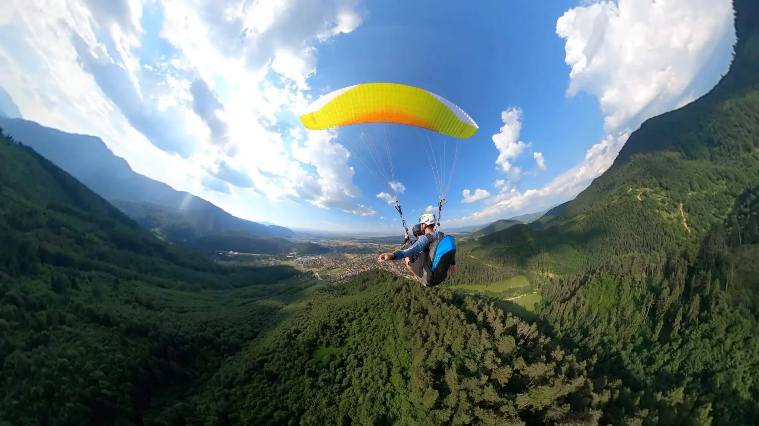 Parapantă în zbor deasupra munților Brașovului — peisaj aerian larg